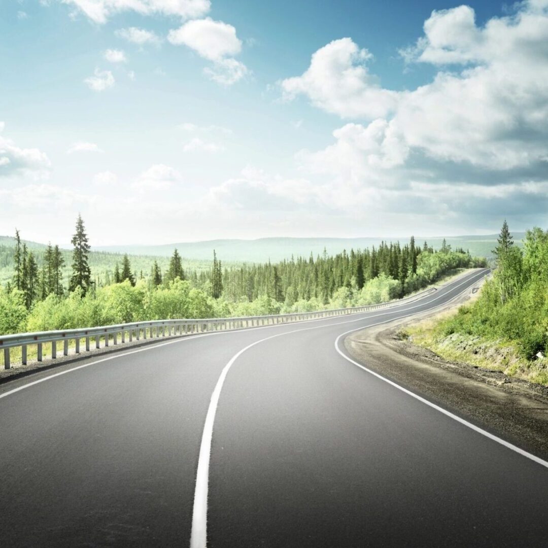 A road with trees and clouds in the background.